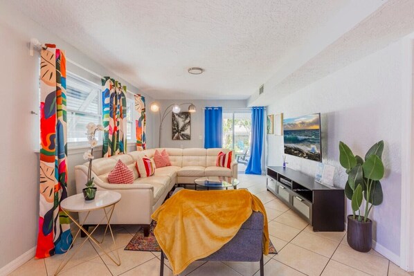 A modern living room with a sofa, coffee table, TV, and potted plants.