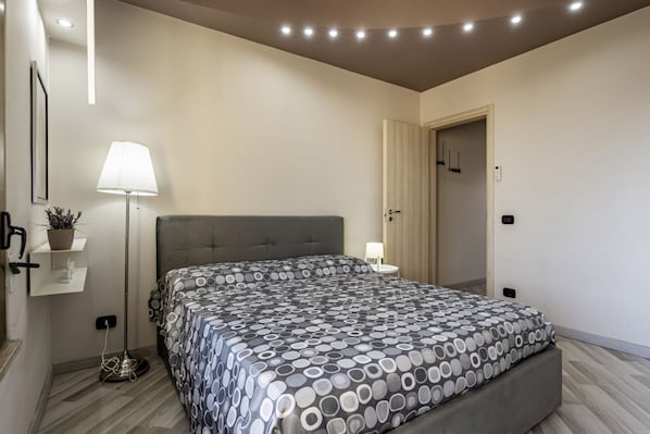 Un dormitorio con cama, lámpara de noche y una puerta.