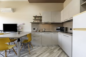 Una cocina moderna con comedor, que incluye un televisor de pantalla plana, sillas amarillas y una orquídea en maceta.