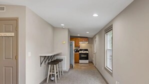 A narrow hallway with a kitchen area at the end, featuring a stove, cabinets, and a window. - Charming 1-bedroom house in fabulous Florence Alabama (Florence)