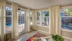 A sunroom with large windows, a pool, and a colorful rug. - Villa Bella with Heated Pool (Largo)