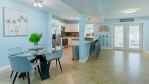 A modern kitchen with white cabinets, stainless steel appliances, and a dining area with a glass table and chairs.