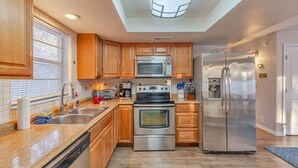 A modern kitchen with wooden cabinets, stainless steel appliances, a dishwasher, and a skylight.