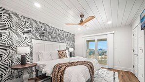 A bedroom with a bed, a ceiling fan, a nightstand, and a view of the outside. - NEW - Ocean View, Heated Pool, Beach, Sleeps 18, Fully Loaded (Gulf Shores)