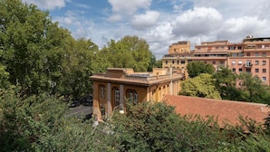 A building with a red-tiled roof, surrounded by trees and other buildings. - GuestHost - Elegant Apartment Testaccio Roma (Rome)