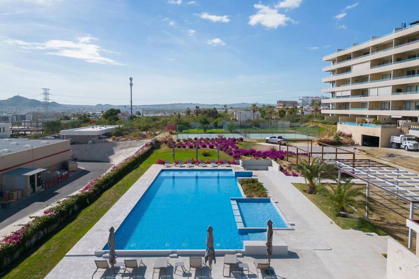 Piscina com espreguiçadeiras e vista para a cidade.