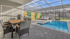 Un espace extérieur abrité comprenant une piscine, une table avec des chaises et des chaises longues.