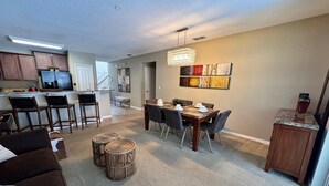 A modern kitchen with dark wooden cabinets, a stainless steel refrigerator, and a bar area with stools.