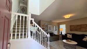 A spacious living area with a staircase, a sofa, a coffee table, and a lamp.