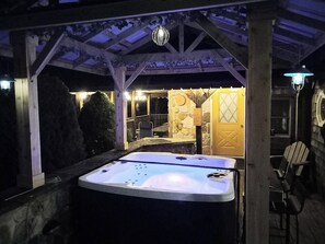 A hot tub under a covered patio with stone walls and a wooden door.