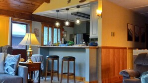 A cozy living room with a wooden ceiling, a dining area with stools, and a kitchen with a bar. - The Golden Eagle Vacation Rental, a 3 minute walk to Timberline Ski Slopes (Davis)