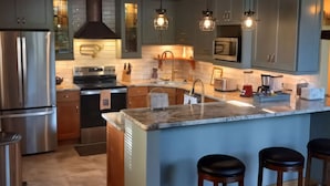 A modern kitchen with a central island, bar stools, stainless steel appliances, and pendant lighting. - The Golden Eagle Vacation Rental, a 3 minute walk to Timberline Ski Slopes (Davis)