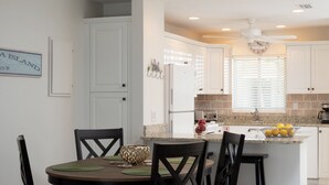 A modern kitchen with white cabinets, a granite countertop, and a dining area with a round table and chairs. - Nautilus 214 by Nautilus Vacations-Beachfront Complex, Heated Pool, Racket Court (Holmes Beach)