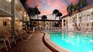 A pool area with lounge chairs and a clear pool, surrounded by multi-story buildings with balconies. - Nautilus 214 by Nautilus Vacations-Beachfront Complex, Heated Pool, Racket Court (Holmes Beach)