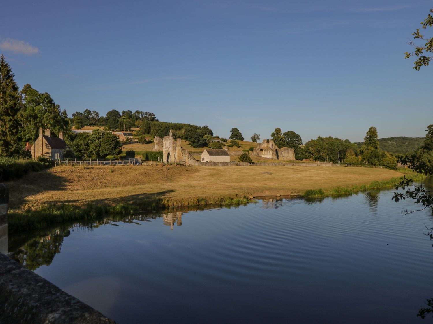 A historic site with ruins, a pond, and surrounding greenery.