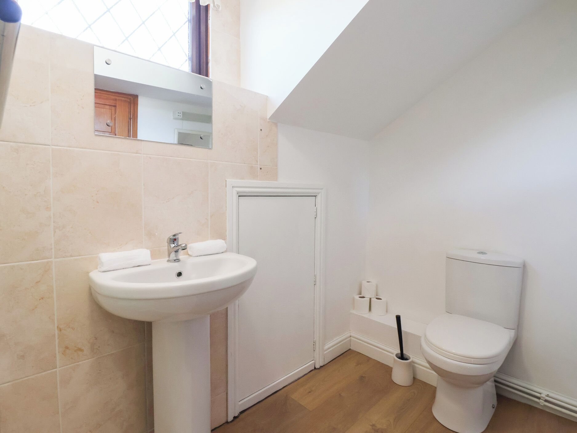 A bathroom with a pedestal sink, toilet, and a mirror above the sink.