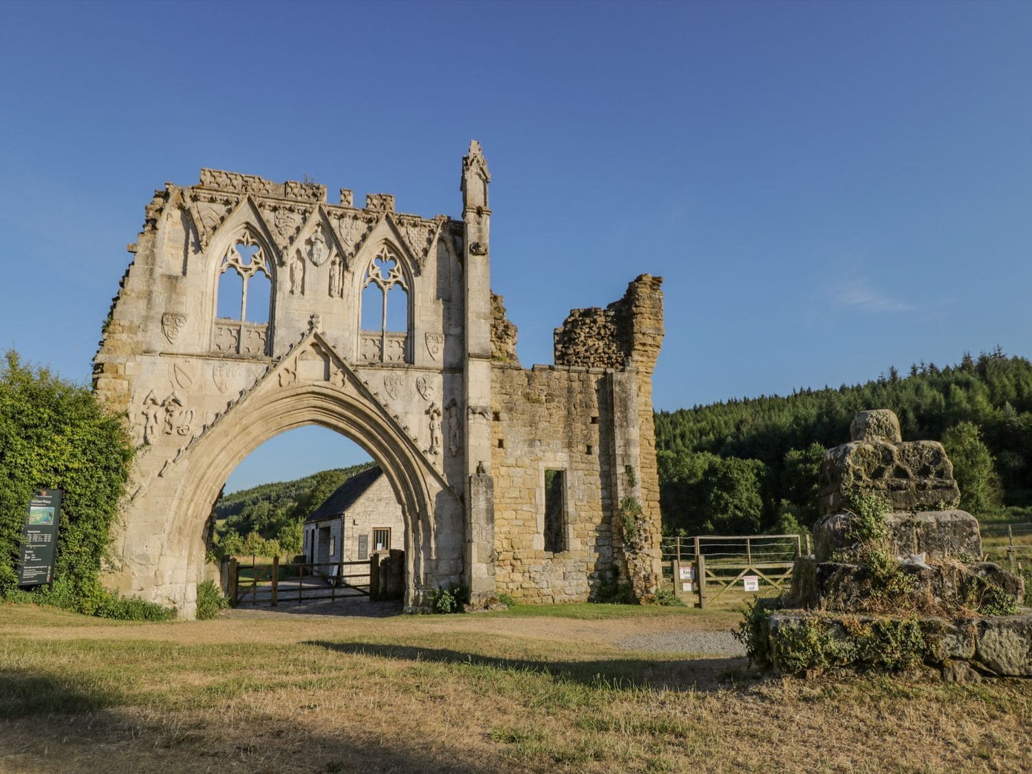 Un arc en pierre d’époque, orné de sculptures complexes, qui mène à un bâtiment en pierre doté d’une porte en bois.