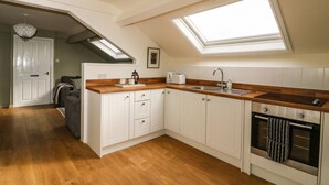 A modern kitchen with white cabinets, wooden countertops, a built-in oven, and skylights. - West Cottage (Malton)