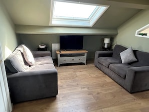Ein Wohnzimmer mit Oberlicht, zwei Sofas, einem Fernseher und einem kleinen Tisch.
