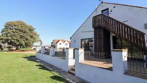 A modern white building with a wooden staircase and a metal fence. - West Cottage (Malton)