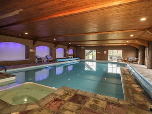 An indoor swimming pool with a wooden ceiling, tiled floor, and lounge chairs. - West Cottage (Malton)