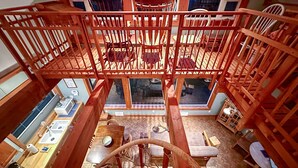 Un intérieur en bois à plusieurs niveaux comprenant un coin repas, une cuisine et une grande fenêtre offrant une vue panoramique.