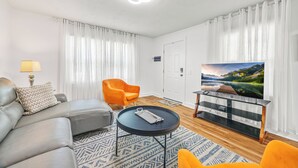 Un salon moderne avec un canapé, une table basse, un téléviseur et un fauteuil.