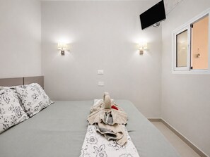 A hotel room with a bed, two wall-mounted lights, a flat-screen TV, and a window with a view. - Sun Port Ocean Views - Renovated & Pool 1 (Puerto Rico)