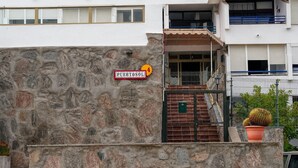 A stone wall with a sign reading 'PUERTOSOLI' and a potted plant. - Sun Port Ocean Views - Renovated & Pool 1 (Puerto Rico)