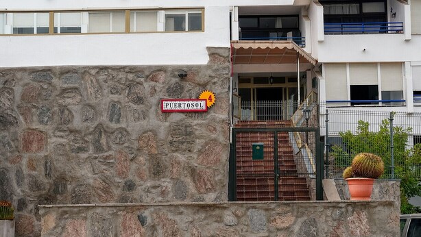 Un muro de piedra con un letrero que dice 'PUERTOSOLI' y una planta en maceta.
