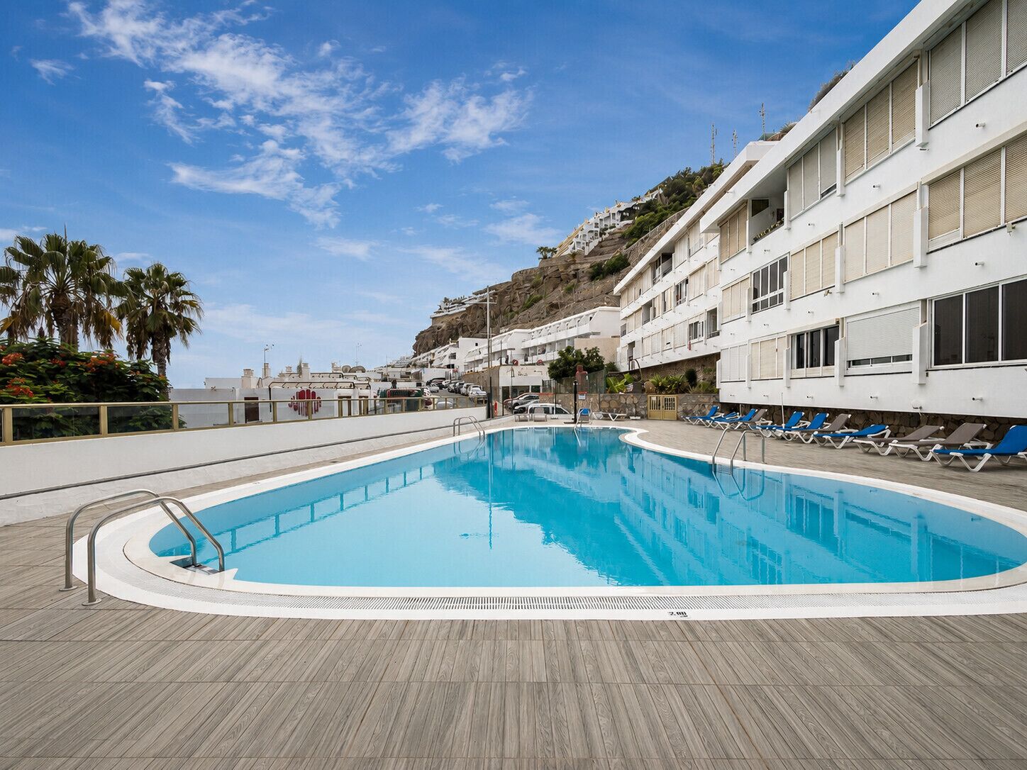 A swimming pool with lounge chairs and a building with balconies.
