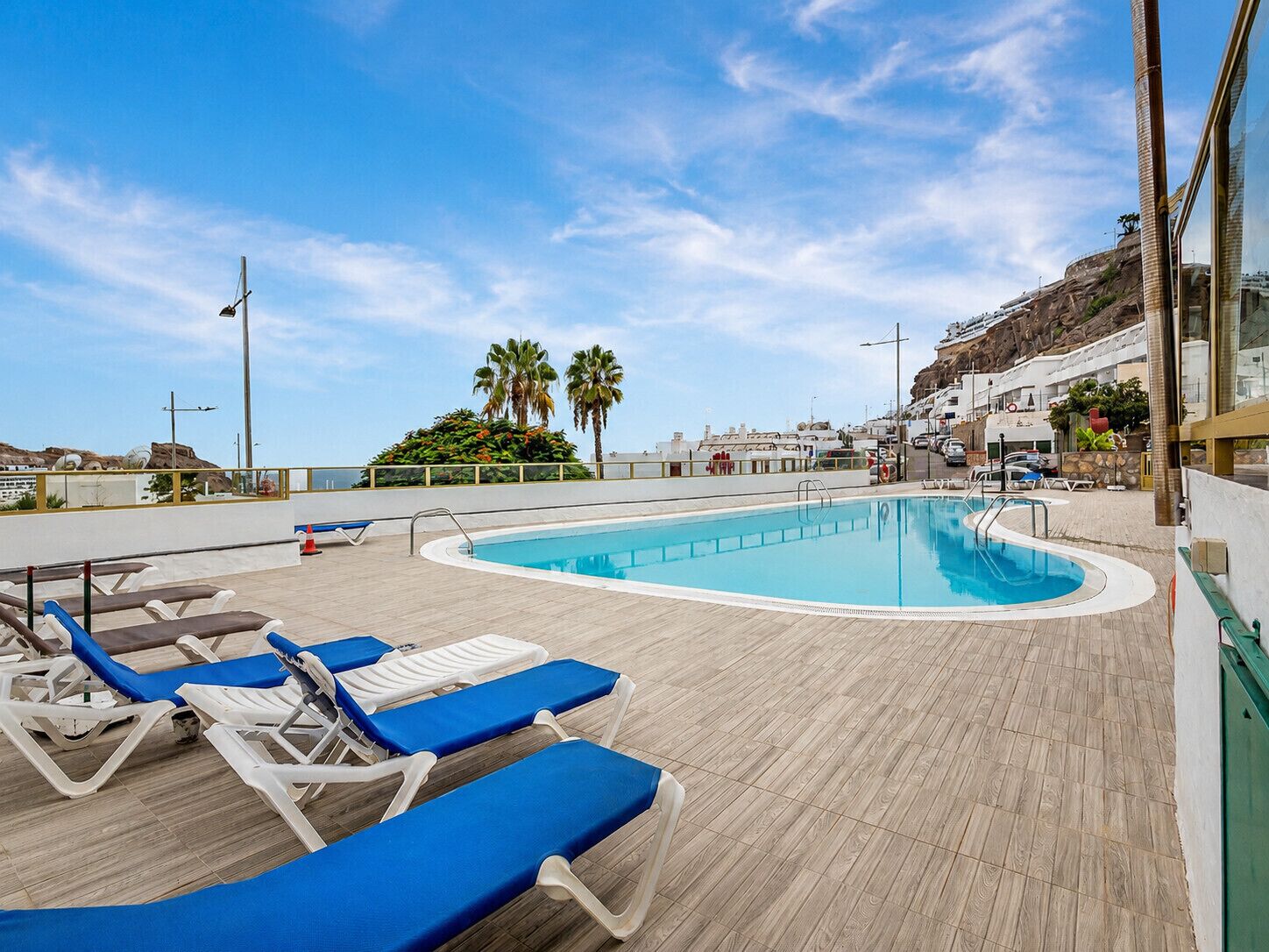 A pool area with lounge chairs and a clear sky.