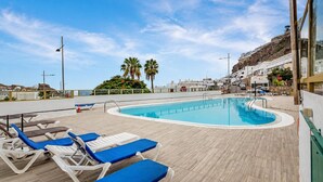 Zona de piscina con sillones de descanso y cielo despejado.