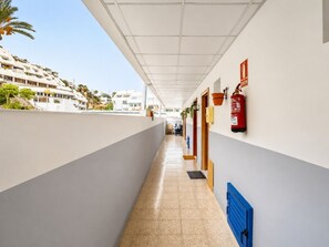 A corridor with a tiled floor, white walls, and a blue storage unit. - Sun Port Ocean Views - Renovated & Pool 1 (Puerto Rico)