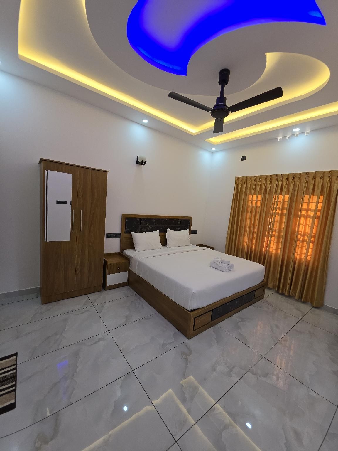 Quarto moderno com cama, guarda-roupa, ventoinha no teto e janela com cortinas.