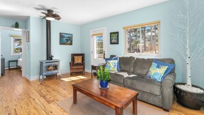 A living room with a fireplace, a sofa, a coffee table, and a potted tree. - Whispering Pines Getaway with hot tub, large deck, game room and wildlife views (Estes Park)