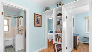 A room with a wooden floor, a white door, a white bookshelf, and a bed with a blue blanket. - Whispering Pines Getaway with hot tub, large deck, game room and wildlife views (Estes Park)