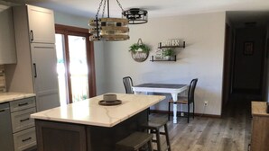 Une cuisine avec un îlot central, une table à manger avec des chaises et un luminaire suspendu.