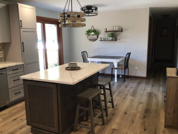 A kitchen with a central island, a dining table with chairs, and a hanging light fixture. - EAA 3 bedroom house in Oshkosh (Oshkosh)