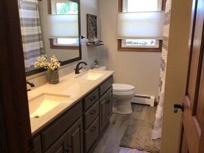 A bathroom with a double sink vanity, a toilet, and a window with blinds. - EAA 3 bedroom house in Oshkosh (Oshkosh)