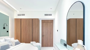 Quarto moderno com cama grande, guarda-roupa de madeira e espelho amplo.