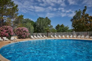 Una piscina con sillas de descanso y una valla.