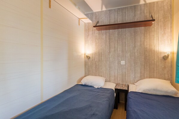 Una habitación con dos camas, un cabecero de madera y una mesita.