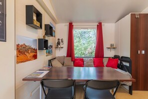 Ein Essbereich mit einem Holztisch, schwarzen Stühlen, roten Kissen und einem Fenster mit roten Vorhängen.