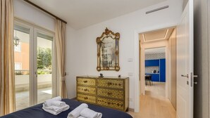 Een slaapkamer met een bed, een dressoir, een spiegel en uitzicht op buiten.