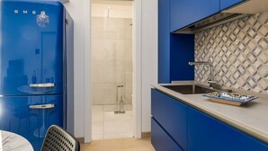 Een moderne keuken met blauwe kastjes, een roestvrijstalen spoelbak en een marmeren aanrecht.