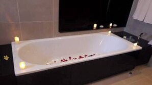 A modern bathroom with a large bathtub, a black vanity, and a mirror above the sink. - Apartment at Anahita 5*Resort : golf & access to Ile aux Cerfs exclusive beach 4 (Beau Champ)