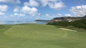A golf course with a flagstick in the center, surrounded by lush greenery and a clear sky. - Apartment at Anahita 5*Resort : golf & access to Ile aux Cerfs exclusive beach 4 (Beau Champ)