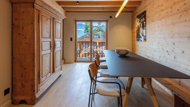 Un comedor con una mesa larga, sillas y un mueble de madera.