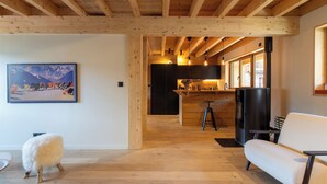 Un interior moderno con vigas de madera, una zona de cocina y un sofá blanco.